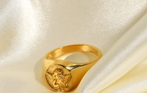 Macro shot of gold-plated stainless steel ring with embossed cupid angel relief on silk