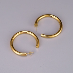 Macro view of gold-plated thick hoop earrings with polished finish and butterfly backs
