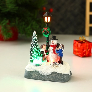 Close-up of glowing Christmas snowman and resin miniature figurines with warm LED lights