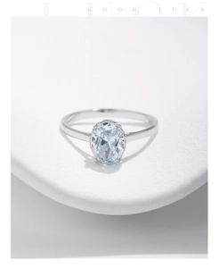 Macro shot of oval light blue gemstone ring with micro-pave setting on white studio stand