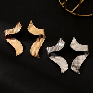 Detailed view of wave-shaped metal earrings with striped texture in gold and silver