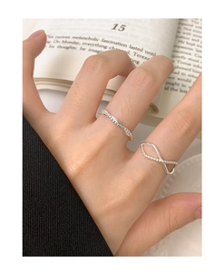 Detailed view of silver minimalist twist ring and cross infinity ring on a finger