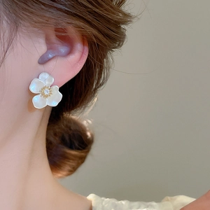Detailed view of floral zircon earring with mother of pearl finish on female ear