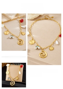 Macro shot of gold charm necklace with sun, red lips, rainbow, and white flower detail