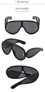 Close-up of black shield sunglasses with grey lenses and golden oval metal details