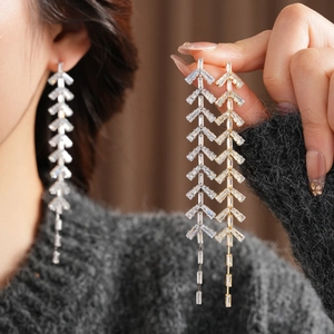 Detail showing long geometric tassel earrings in gold and silver plating with cubic zirconia
