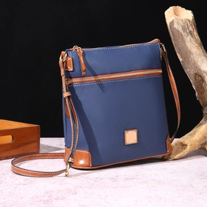 Detail of pebbled blue leather crossbody bag with brown trim and gold-tone hardware
