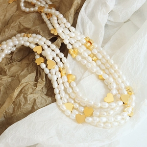 Elegant multi-layer pearl necklace featuring polished gold heart charms and baroque beads