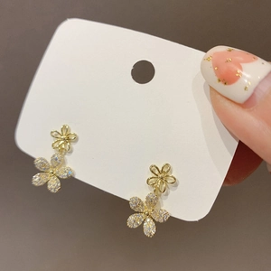 Macro shot of gold floral earrings with double layer crystals and zircons on white card