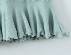 Dettaglio del tessuto in maglia a coste verde menta con un delicato orlo a volant