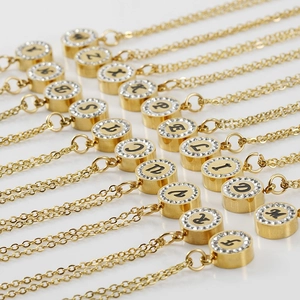 Colliers en acier doré 18K avec pendentifs lettres et strass brillants sur fond blanc