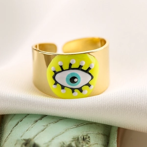 Macro shot of 18K gold plated evil eye ring with yellow enamel on white silk
