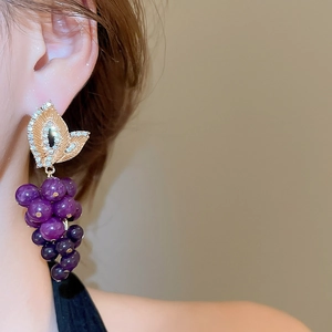 Vue macro de boucles d'oreilles grappes violettes avec feuille dorée et brillants