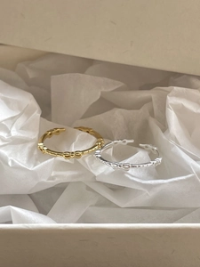 Detailed view of gold and silver bow relief rings inside a stylish beige jewelry gift box
