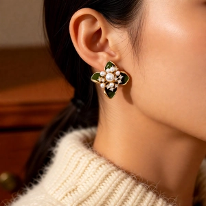 Détail de boucles d'oreilles fleur vintage vertes avec perle centrale et plaqué or 18k