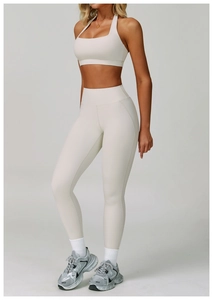 Full view of cream high-waisted yoga leggings and halter sports bra set for women