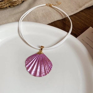 Detail of pink shell pendant necklace with gold accents on white decorative plate