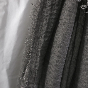 Macro shot of dark grey cotton linen scarf featuring crinkled texture and frayed edges