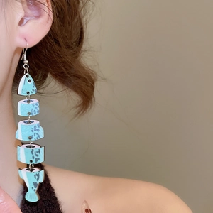 Close-up of mint green wooden fish bone pendant earring worn on ear for vintage style