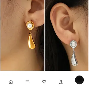 Detail view of teardrop pearl earrings in gold and silver plating on model