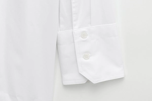 Close-up of white long-sleeved shirt featuring double-button cuffs and twill fabric texture