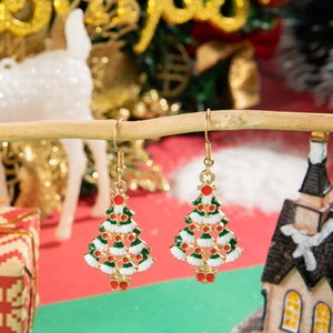 Detail of gold-plated Christmas tree earrings with red and white enamel on a festive tree