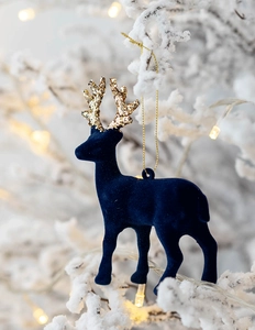 Close-up of a blue flocked reindeer ornament with gold glitter antlers on a snowy branch