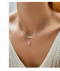 Dettaglio di una collana a due strati in argento 925 con pendente a croce e zirconi lucenti
