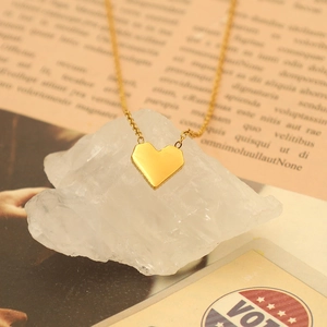 Detailed close-up of a 18k gold-plated heart pendant on a natural white crystal stone