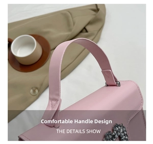 Gros plan du sac à main rose avec boucle cœur en strass et poignée de transport