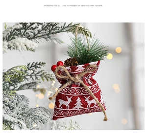 Christmas burlap gift bag with pine cone and berry hanging on a snowy tree branch