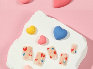 Detail of nude press on nails featuring red and blue heart patterns with white dots