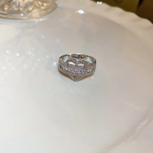 Detailed view of silver heart ring with baguette cut cubic zirconia on a white plate