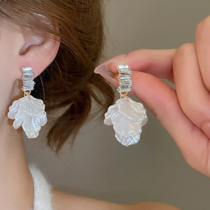 Detail of white pleated petal drop earrings with rectangular zircon accents and gold plating