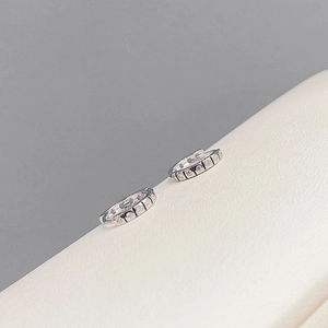 Close-up of S925 silver C-shaped hoop earrings with micro-inlaid zircon on leather