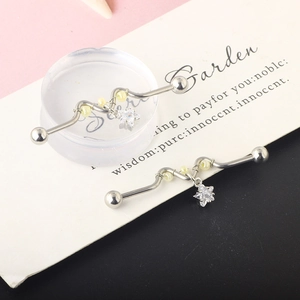Macro shot of two wavy silver industrial barbell earrings with star zircon pendants