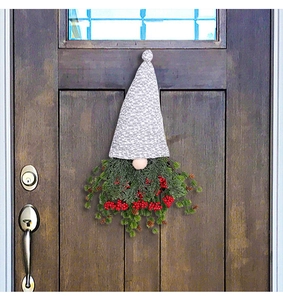 Gros plan d'une couronne de gnome de Noël avec bonnet gris et baies rouges sur une porte en bois