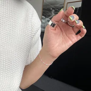 Close-up of 925 sterling silver rings and a delicate pink bead bracelet on a model