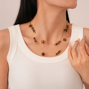Close-up of double-layer necklace with gold beads and tiger eye stones on a model