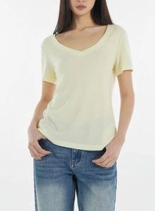 Close-up of the breathable tencel wool fabric texture on a pale yellow V-neck t-shirt