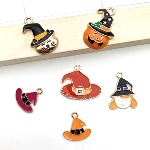 Close-up of assorted Halloween enamel charms featuring pumpkins and witch hats for jewelry