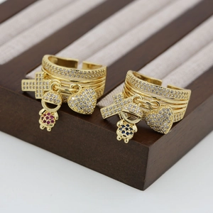 Detail of 18K gold-plated open ring with cross, boy/girl, and heart charms with zircons