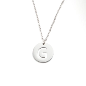 Détail d'un collier avec pendentif rond argenté et motif de la lettre G ajourée