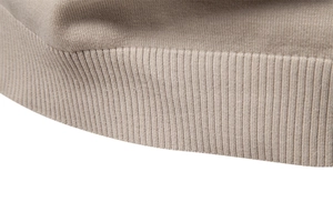 Détail d'un pull en maille beige montrant l'ourlet côtelé et la texture du tissu
