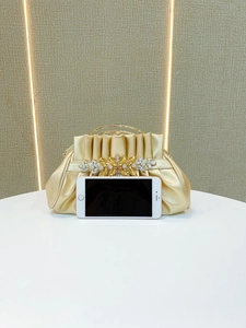 Gold evening clutch bag featuring pleated fabric and rhinestone flowers with smartphone for scale