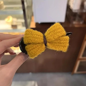 Close-up of yellow knitted bow hair claw clip made of textured wool material