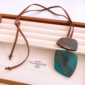 Close-up of vintage irregular horn pendants on a textured tray with jewelry card