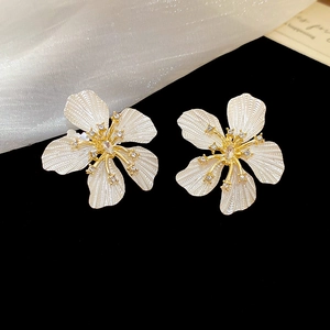 Macro detail of cream floral stud earrings with textured petals and zircon center