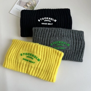 Detail von drei Strickstirnbändern in Schwarz, Grau und Gelb mit Stickerei-Schriftzug