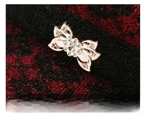 Detail of a golden hollow butterfly brooch with rhinestones on a red and black knit hat
